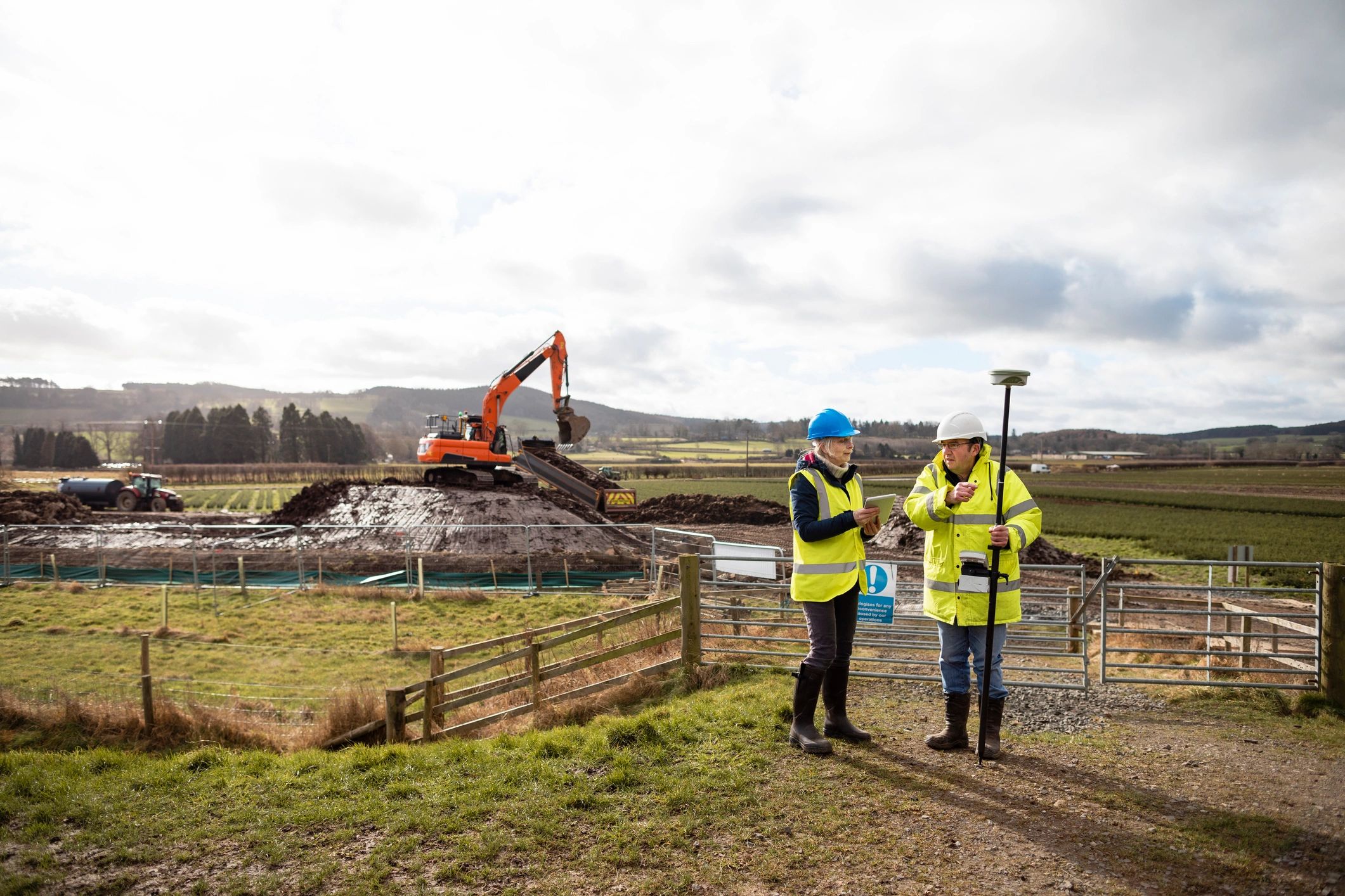 Engineering crew coordinating civil works beside an excavator